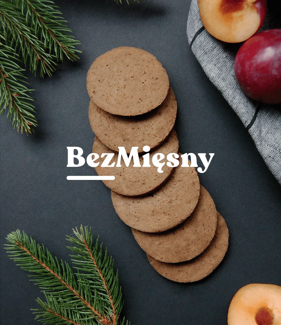 Plant-based pork loin slices fanned out on a dark background among fir sprigs and fresh plums, with the BezMięsny wordmark overlaid