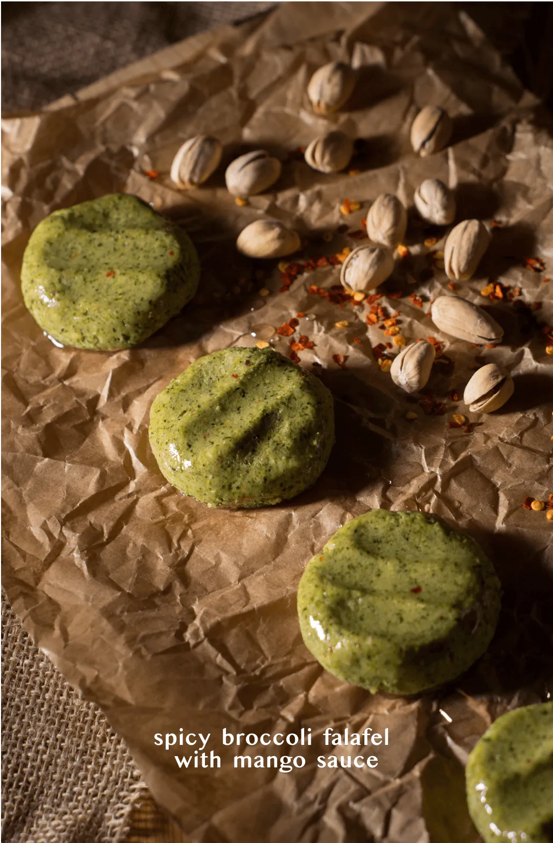 Close-up of green broccoli falafel glazed with mango sauce on crumpled baking paper scattered with pistachios