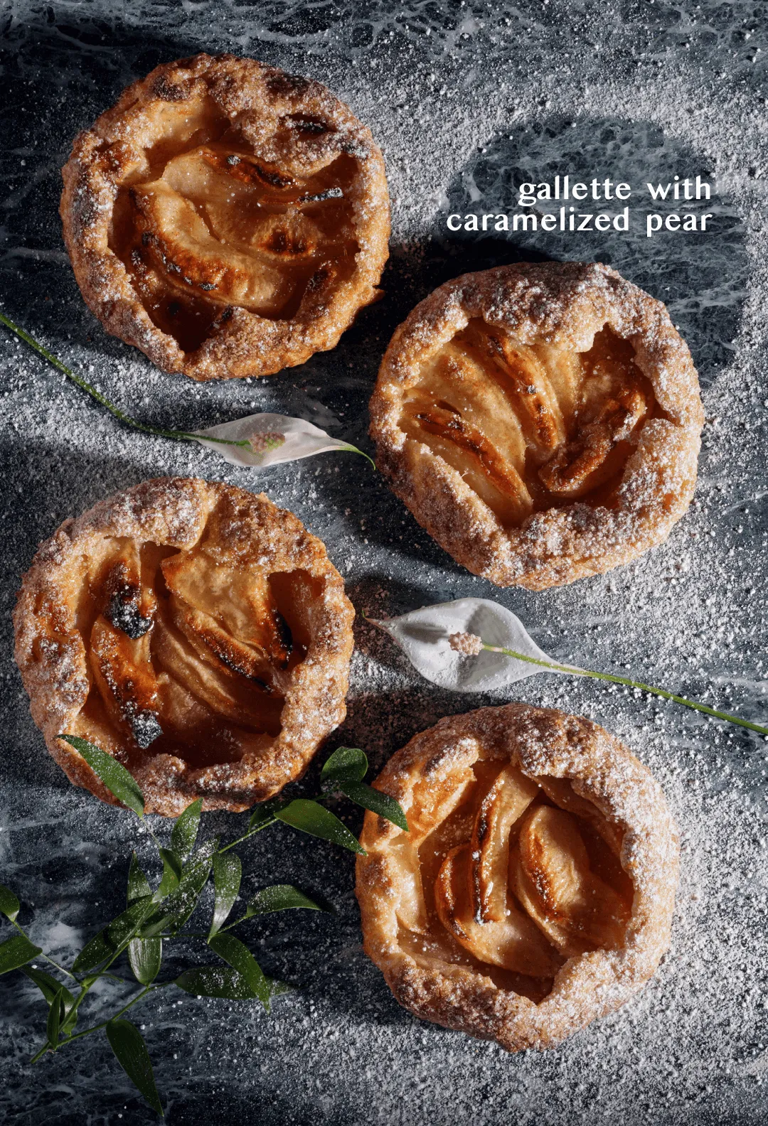 Three galettes with caramelized pear dusted with icing sugar on dark stone, titled "gallette with caramelized pear"