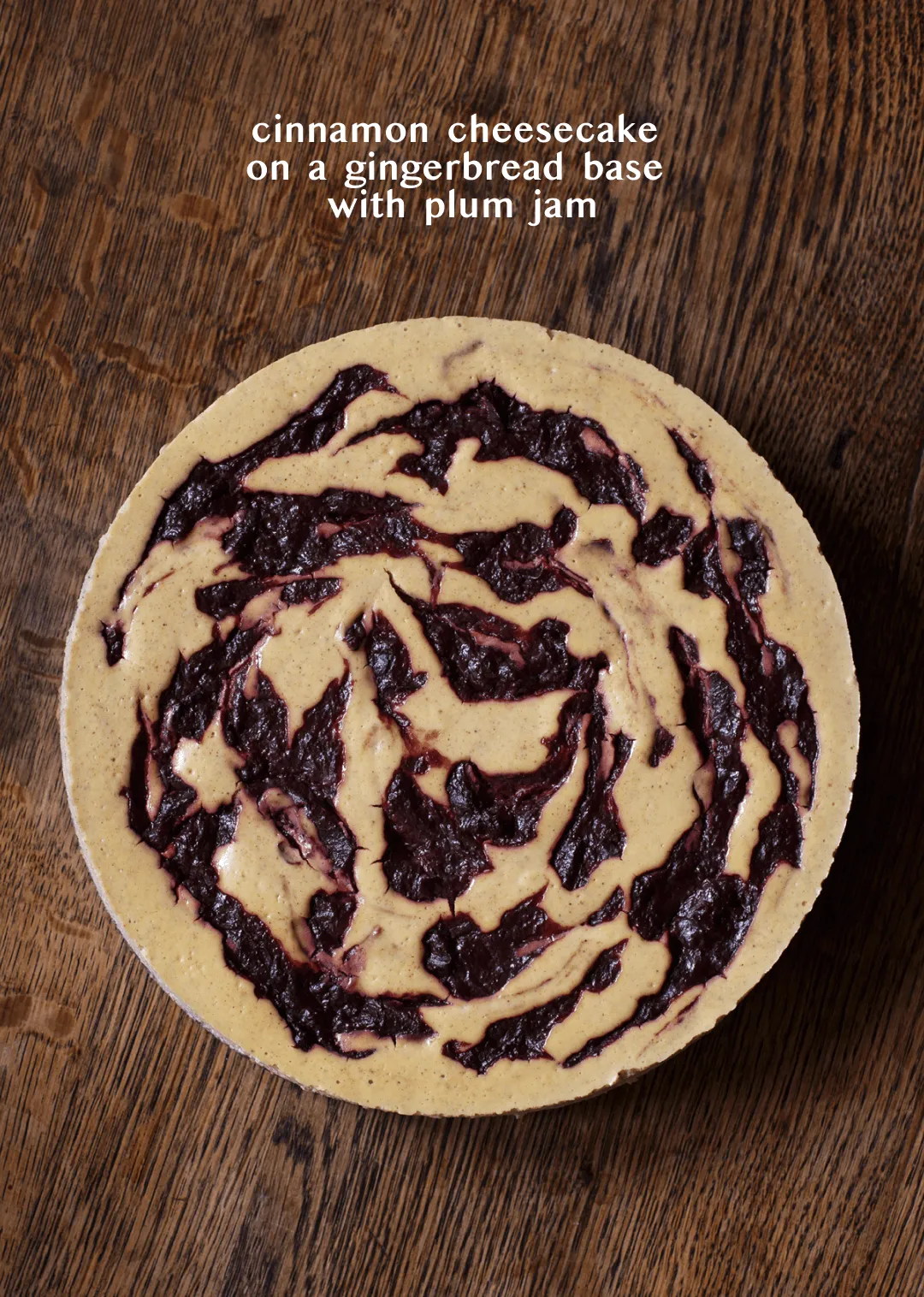 Overhead shot of a cinnamon cheesecake swirled with plum jam, titled "cinnamon cheesecake on a gingerbread base with plum jam"